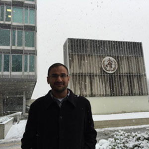 On a snowy morning, Dr. Singh stands in front of the emblem of WHO.